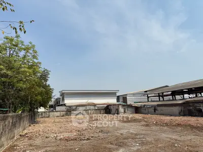 Spacious vacant land with potential for development, surrounded by industrial buildings.