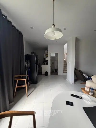 Modern living room with minimalist decor and natural light, featuring a cozy seating area and sleek lighting.