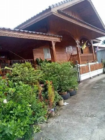 Charming traditional wooden house with lush garden and spacious porch.