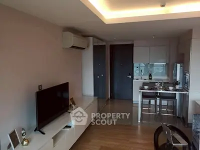 Modern living room with open kitchen, featuring sleek furniture and ambient lighting.