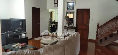 Spacious living room with cozy seating and elegant staircase in a charming home.