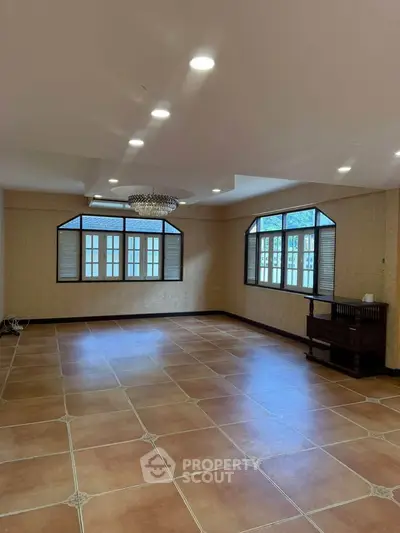 Spacious living room with elegant chandelier and large windows for natural light.