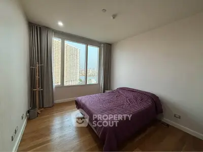 Spacious bedroom with large window offering city views, featuring a cozy bed and elegant curtains.