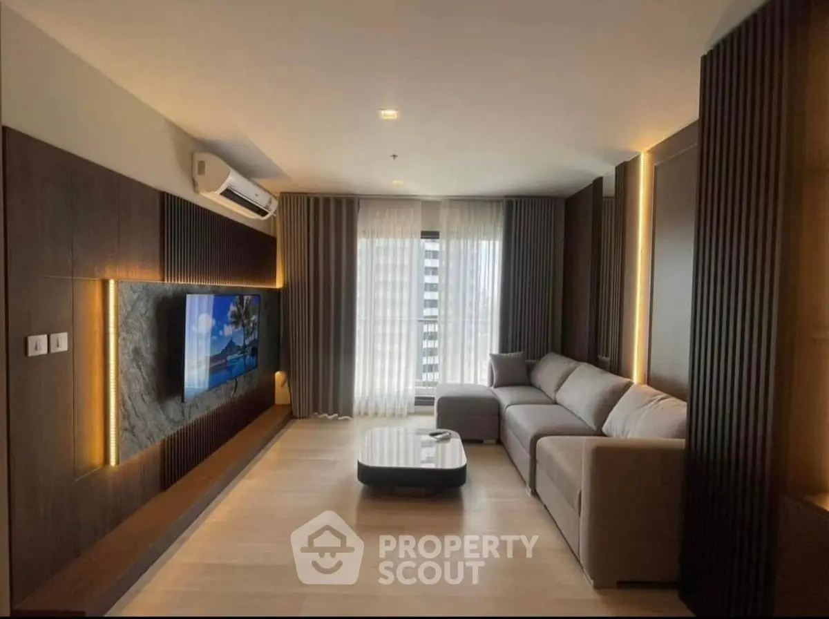 Modern living room with sleek design, large TV, and cozy sectional sofa in a stylish apartment.