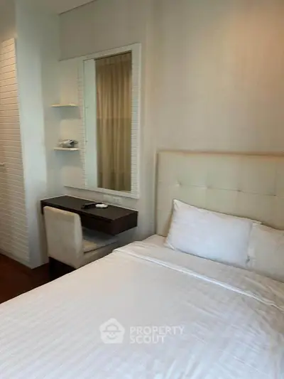 Cozy bedroom with plush bed and elegant study desk, perfect for relaxation and productivity.