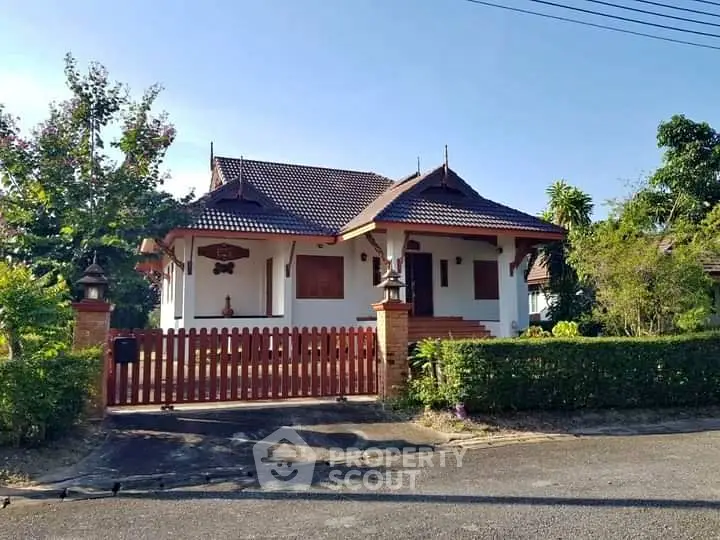 Charming traditional-style house with lush garden and wooden fence in serene neighborhood.