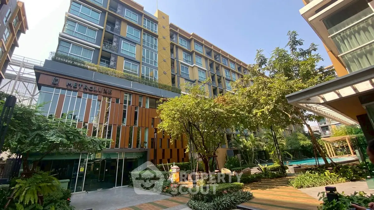 Modern condominium building with lush greenery and pool in urban setting