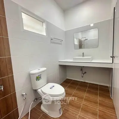 Modern bathroom with sleek design and wooden tile flooring, featuring a white toilet and sink.