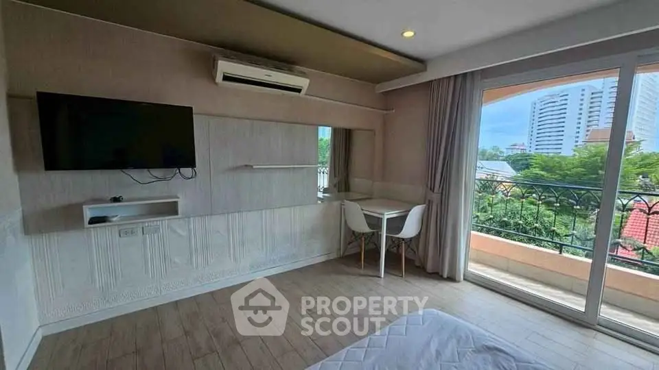 Modern bedroom with balcony view and wall-mounted TV in urban apartment