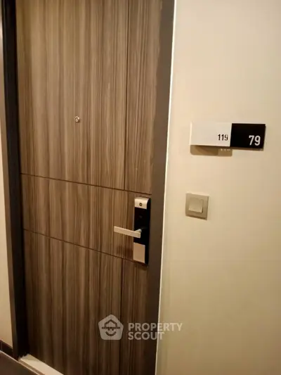 Modern apartment entrance with sleek wooden door and room number signage.