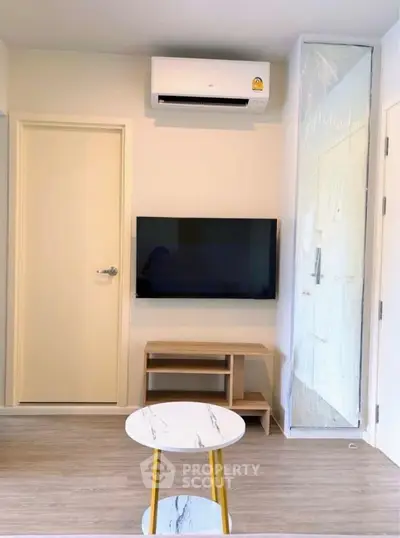 Modern living room with wall-mounted TV and air conditioning unit, featuring sleek furniture and minimalist design.