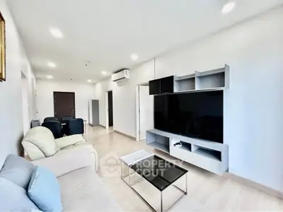 Spacious modern living room with sleek furniture and large TV, perfect for relaxation and entertainment.