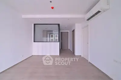 Spacious modern living room with sleek flooring and air conditioning in a minimalist apartment.