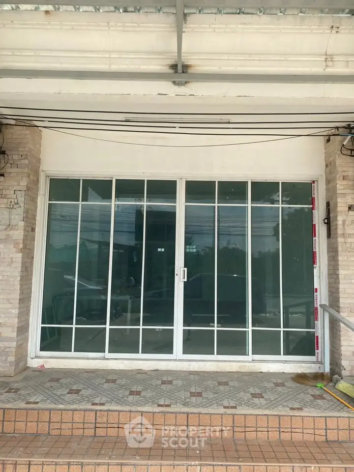 Spacious commercial property entrance with large glass sliding doors and tiled steps.
