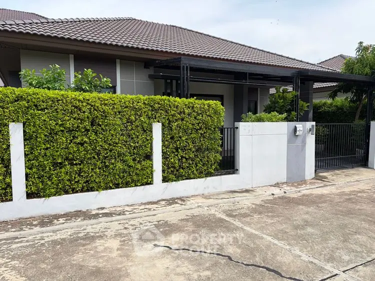 Charming suburban house with lush green hedge and modern gate, perfect for family living.