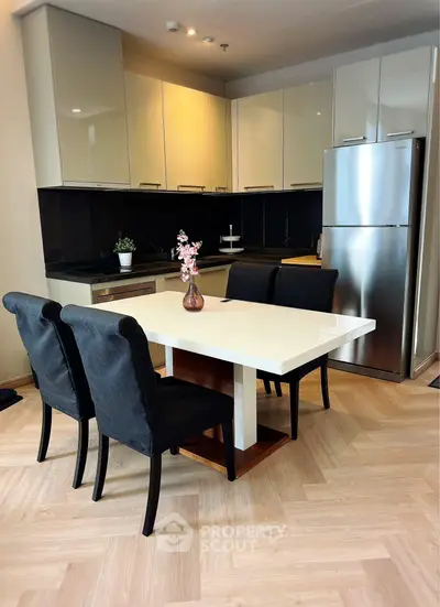 Modern kitchen with sleek cabinets, stainless steel fridge, and elegant dining area.
