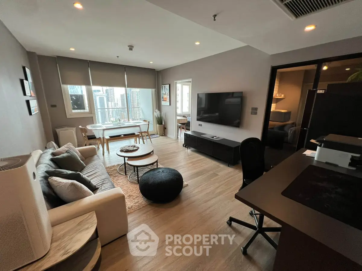 Modern living room with city view, stylish furniture, and open layout in a high-rise apartment.