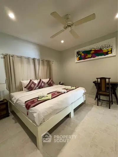 Cozy bedroom with elegant decor and ceiling fan, perfect for relaxation.