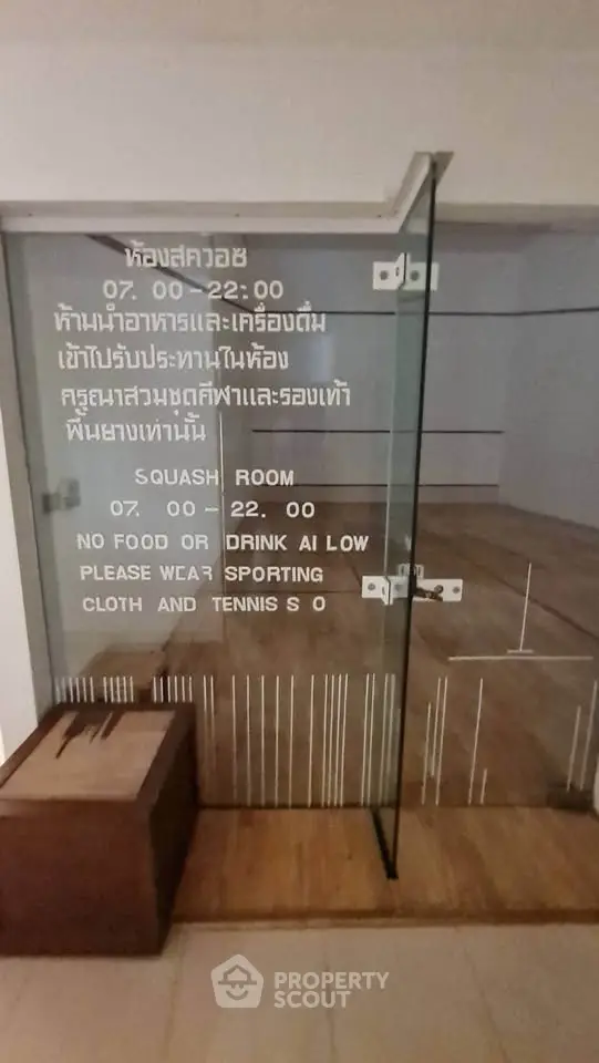Squash court with glass door and rules displayed, modern sports facility