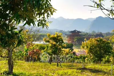 Scenic view of lush garden with mountains and unique architecture in the background.
