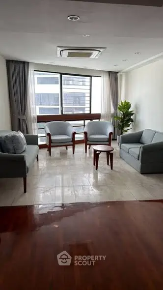 Spacious living room with modern furniture and large window offering city view.