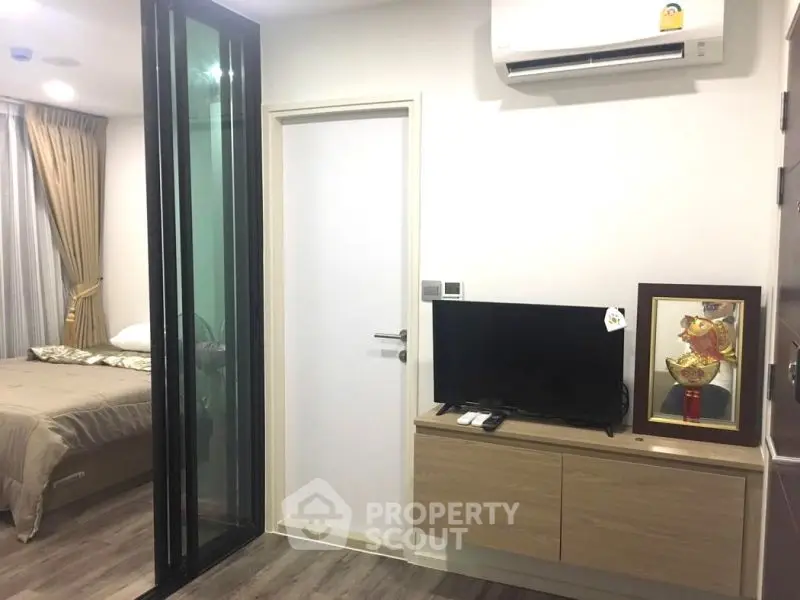 Modern apartment interior with bedroom and living area, featuring sleek design and air conditioning.