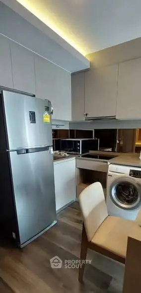 Modern kitchen with sleek appliances and washing machine in compact layout.