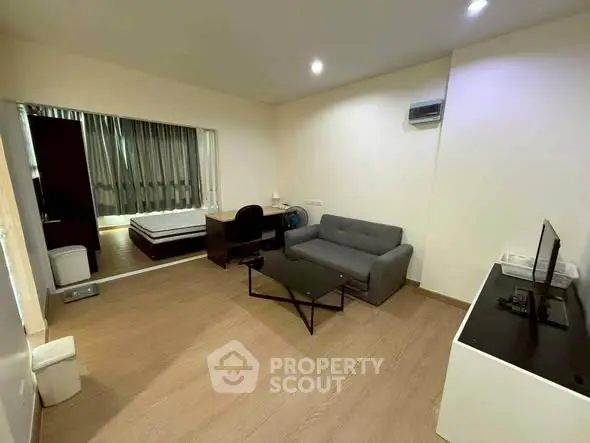 Modern studio apartment with cozy living area and bedroom, featuring sleek furniture and ambient lighting.
