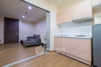 Modern open-plan kitchen and living room with sleek wooden flooring and contemporary furniture.