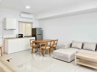 Modern open-plan living room with kitchen, dining area, and cozy sofa in a bright, minimalist design.