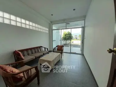 Spacious living room with elegant wooden furniture and large glass doors leading to a scenic view.
