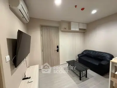 Modern living room with sleek furniture and wall-mounted TV in a cozy apartment.