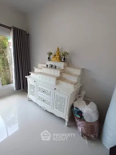 Elegant living room corner with a stylish white cabinet and Buddha statue, perfect for serene home decor.