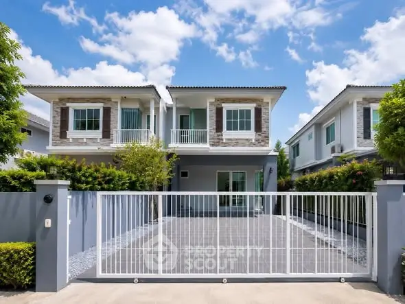 Modern two-story house with gated driveway and lush greenery