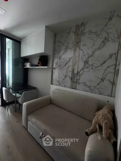 Modern living room with elegant marble accent wall and cozy sofa in a stylish apartment.