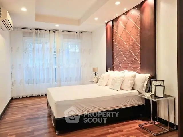 Elegant bedroom with modern decor and ambient lighting, featuring hardwood floors and a stylish accent wall.