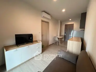 Modern living room with sleek furniture and open layout, featuring a cozy sofa and flat-screen TV.