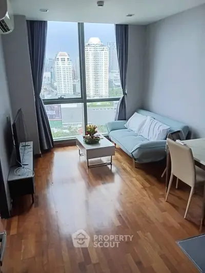 Modern living room with city view, hardwood floors, and stylish furniture in a high-rise apartment.