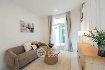 Modern living room with cozy sofa, stylish decor, and natural light from large windows.