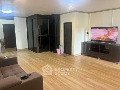 Spacious living room with modern decor and large TV, perfect for relaxation.