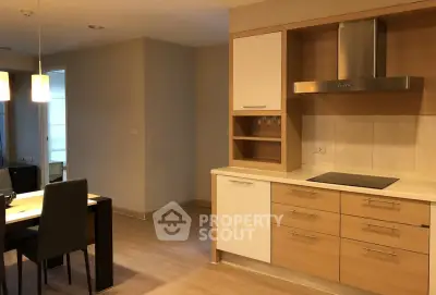 Modern kitchen with sleek cabinetry and dining area in open layout apartment.