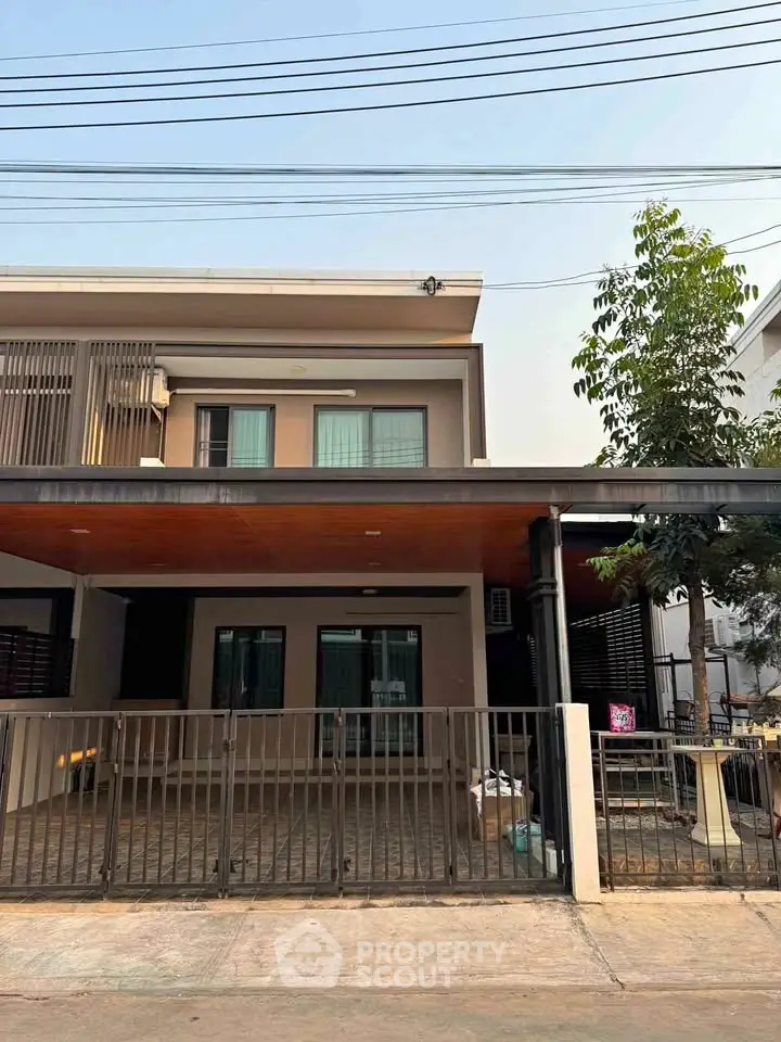 Modern two-story house with gated driveway and contemporary design.