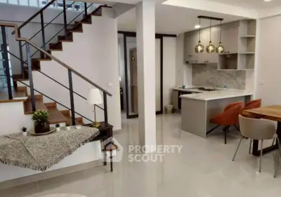 Modern open-plan living area with stylish kitchen and elegant staircase, perfect for contemporary living.