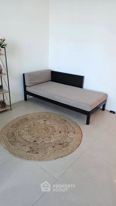 Minimalist living room with daybed and woven rug, perfect for modern urban living.