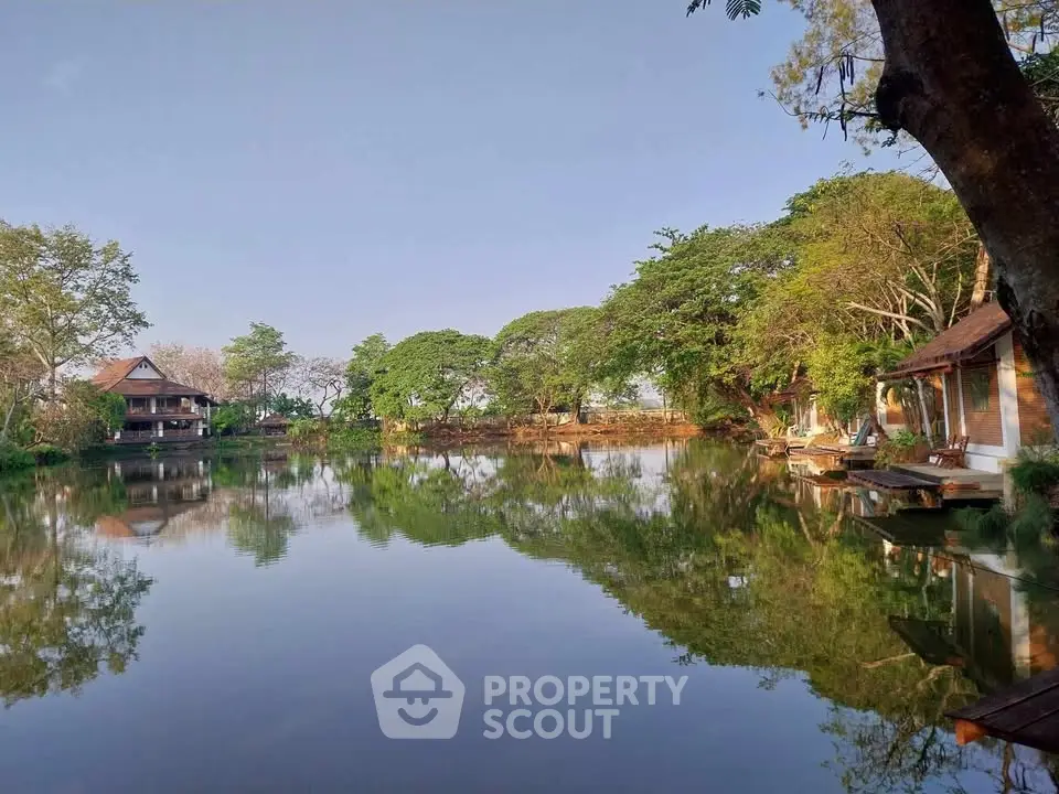Serene lakeside view with charming houses and lush greenery, perfect for tranquil living.