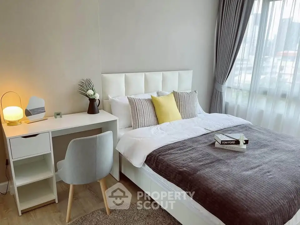 Modern bedroom with stylish decor, featuring a cozy bed, elegant desk, and large window with city view.