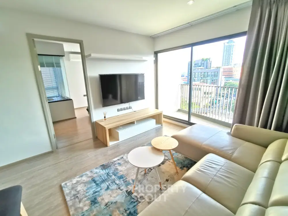 Modern living room with large TV and city view balcony in luxury apartment.