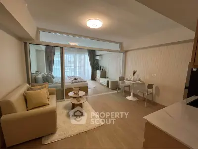 Modern open-plan living room with cozy seating and dining area, featuring elegant decor and natural light.