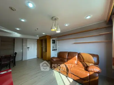 Spacious living room with leather sofa and modern lighting in a bright apartment.