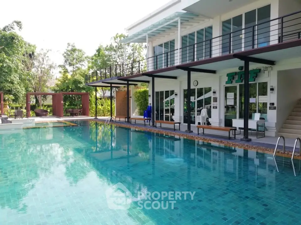 Luxurious poolside view of modern building with lush greenery, perfect for relaxation and leisure.